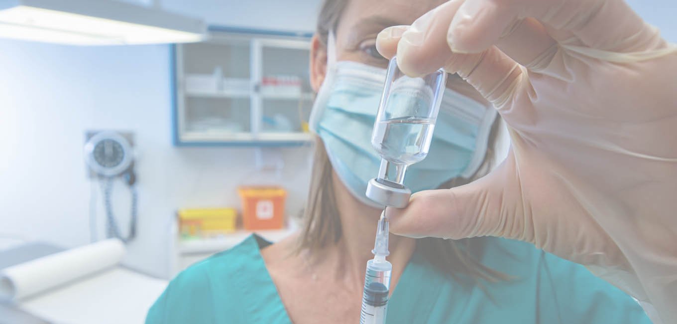 Девушка-медик собирает в шприц лекарственный раствор из стеклянного пузырька