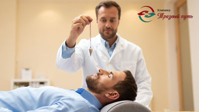 Пациент лежит на кушетку, рядом врач проводит гипнотический сеанс